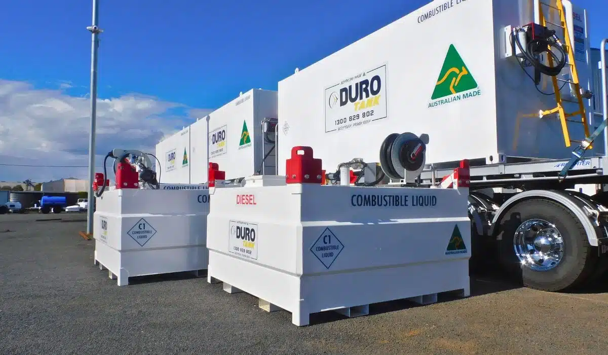 Two white Durotank self-bunded fuel tanks fitted with red diesel dispensing pumps and hose reels, parked beside a fuel truck on a worksite.